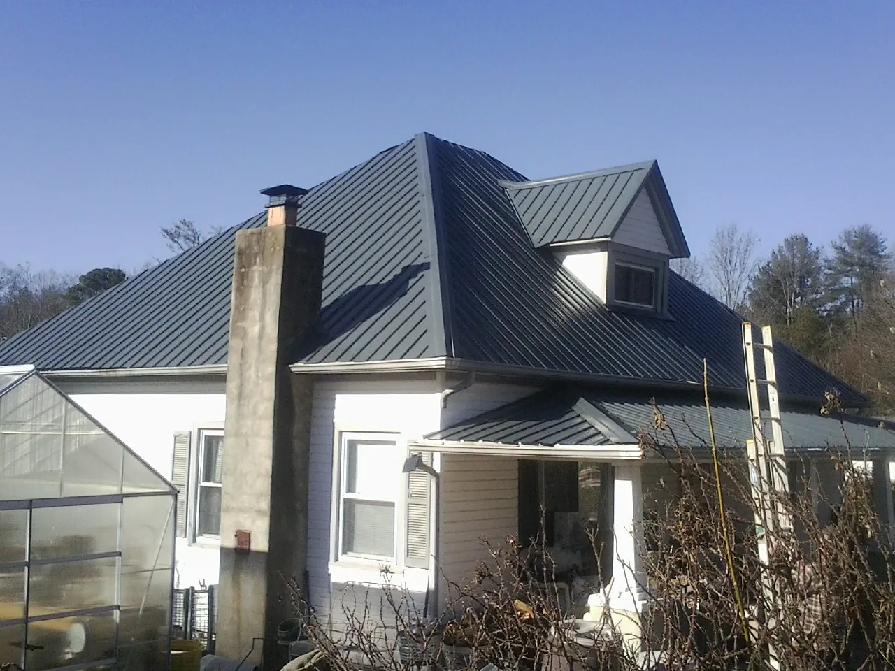 Dark blue standing seam metal roof on a white farmhouse with dormer — Slate & Tile Roof Repair by Roofing Brothers in Reedville