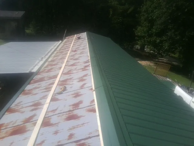 Old rusted panels beside newly installed green metal roofing — Wind Damage Roof Repair by Roofing Brothers in Reedville