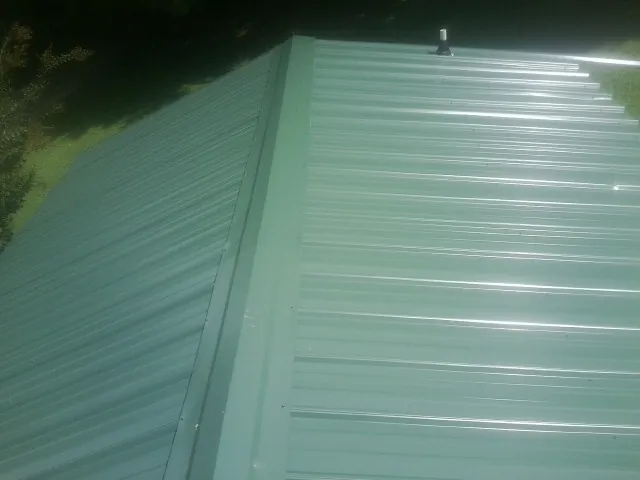 New green metal panels meeting at the ridge of a roof — Flat Roof Repair work by our crew in Reedville