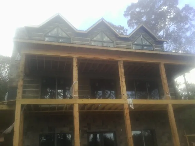 Dormers and porch framing on a large log home under construction — Roof Coating work by our crew in Reedville