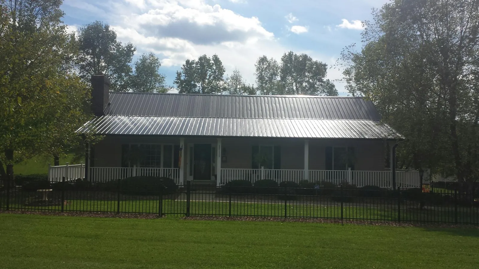 Gray metal roof on a brick ranch with a full width front porch — Gutter Guard Installation work by our crew in Reedville