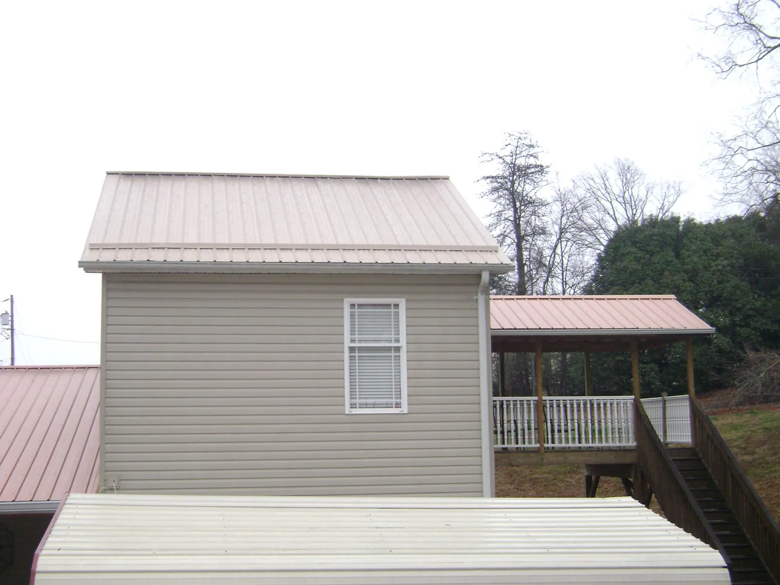 Tan metal roofs on a two story addition and attached porch, from a Roof Replacement job in Reedville